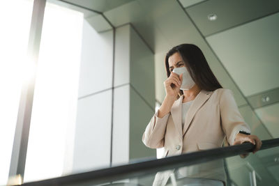 Full length of man using mobile phone while standing on ceiling