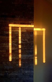 Low angle view of illuminated lamp on wall in building