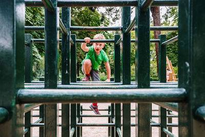 Full length of boy standing on railing at playground