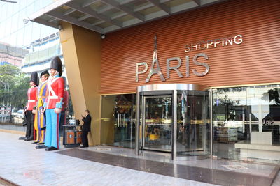 People standing on footpath by building in city