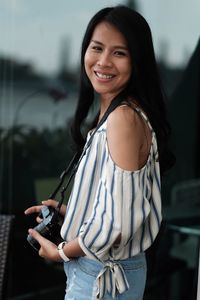 Side view portrait of young woman holding camera