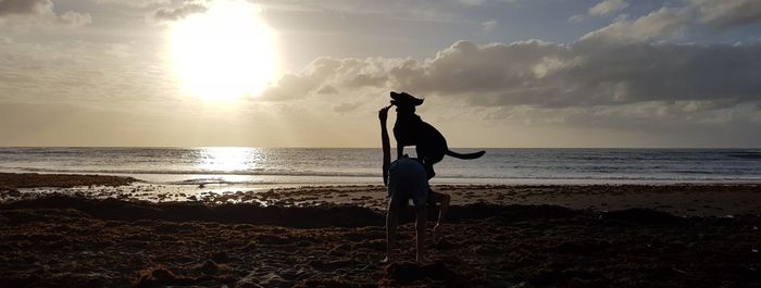 Man standing on beach against sky during sunset