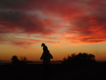 Side view of silhouette man sitting on field at sunset