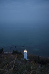 Lighthouse by sea against sky