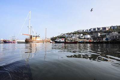 Sailboats moored in sea against sky