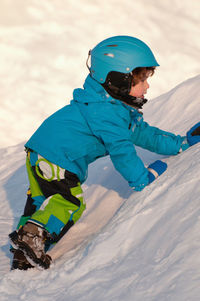 Side view of boy playing on snow covered mountain