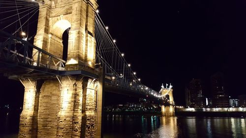 Low angle view of illuminated bridge over river at night