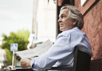 Mature businessman reading newspaper outdoors