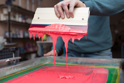 Midsection of man with paint on machinery in factory