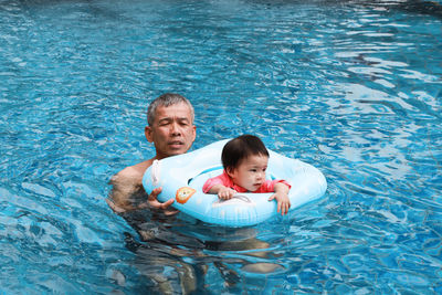 High angle view of father and daughter swimming in pool