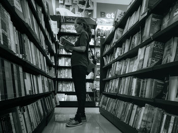 Full length of woman reading book in library