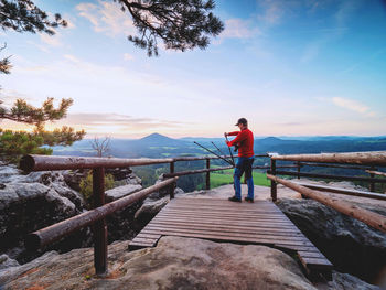 Hiker setting tripod legs upside down with camera in ball head. hurry up to use tripod on viewpoint