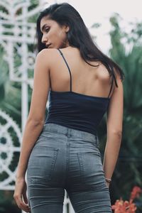 Midsection of young woman standing against trees