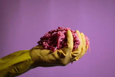 Close-up of hand holding meat against purple background