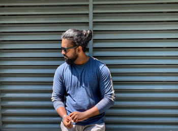 Side view of young man standing against wall