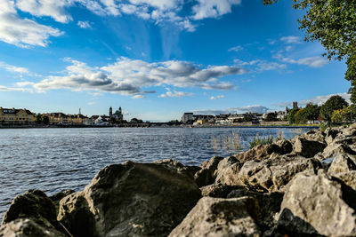 Scenic view of river by city against sky