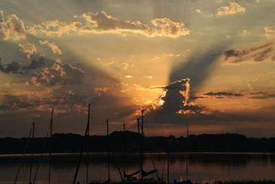 Scenic view of lake by silhouette trees against sky during sunset 