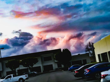 Cars on road against dramatic sky