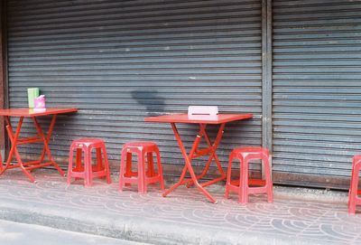 Chairs and tables on sidewalk against building in city