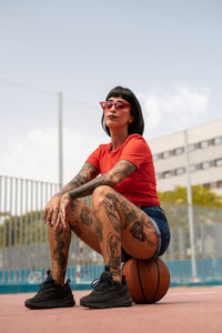 Caucasian girl with tattoos and short black hair on a sports court