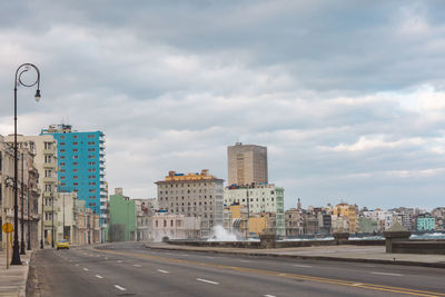 Street by buildings against sky in city