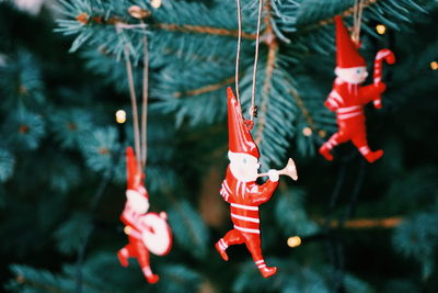 Close-up of red figurines hanging on christmas tree