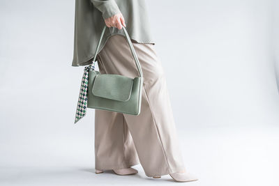 Low section of woman holding bag against white background