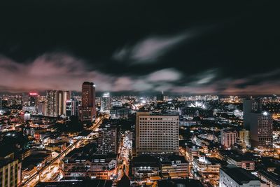 High angle view of cityscape against cloudy sky at night