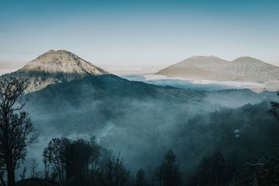 Scenic view of foggy mountains against sky