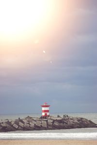 Lighthouse by sea against sky