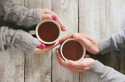 Cropped hand of woman holding coffee on table