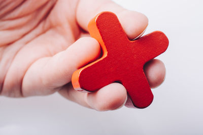 Close-up of hand holding cross shape against white background