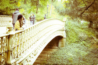 People walking on footbridge in forest