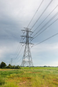 Low angle view of electricity pylon on field against sky