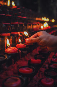 Cropped hand of person burning red candle in church