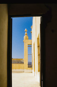 Building against blue sky seen through window