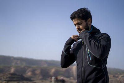 Young indian fit boy jogging in the morning near a lake situation in middle of a mountain area.