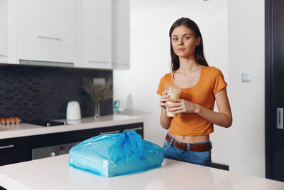 Portrait of young woman drinking from bottle at home