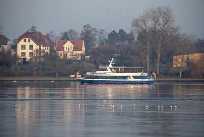 Boats on lake by buildings against sky