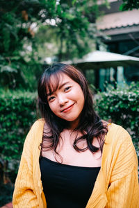 Portrait of smiling woman standing against plants