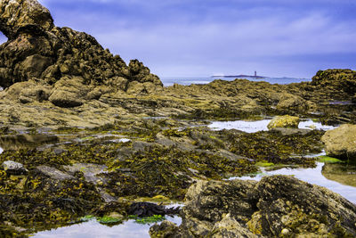 Rock formation by sea against sky