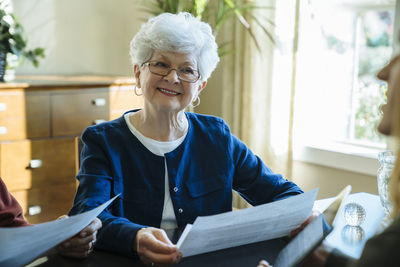 Senior woman looking away while holding documents in financial advisor's office