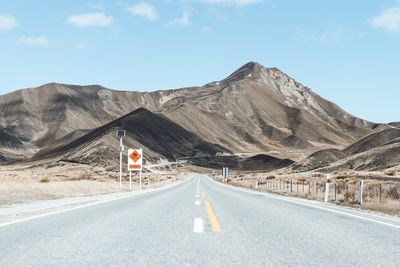 Road leading towards mountains against sky