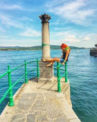Woman standing by sea against sky