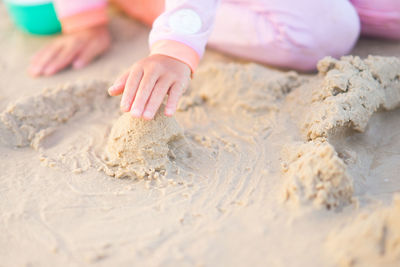 Low section of girl making sandcastle on beach