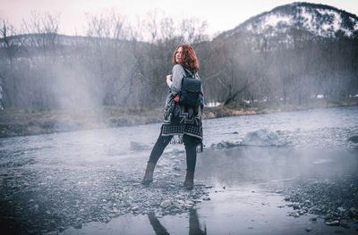 Full length of woman standing in lake during winter