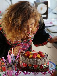 Woman burning candle on cake at table