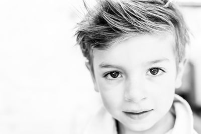 Close-up portrait of cute boy against wall at home