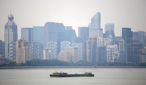 Nautical vessel on river by buildings against sky in city