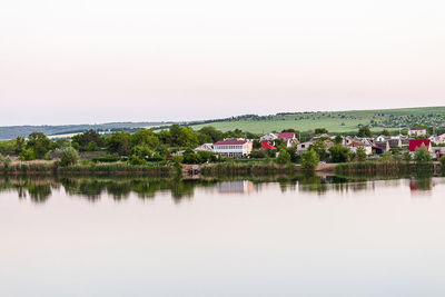 Scenic view of lake by buildings against clear sky